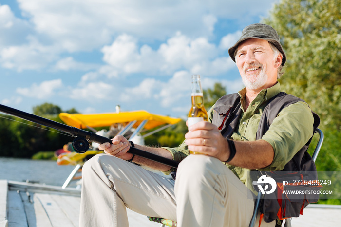 Man smiling while fishing and drinking beer