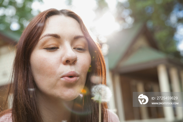 妇女在户外吹蒲公英种子的特写