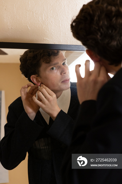 non-binary caucasian person with short hair getting dressed in mirror