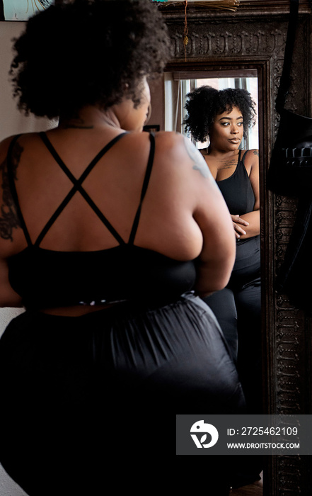 Black woman looking in mirror admiring herself