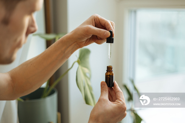 Vitamins and supplements. Hand holding pipette of Hemp oil. Close up man uses CBD oil. Medical canna