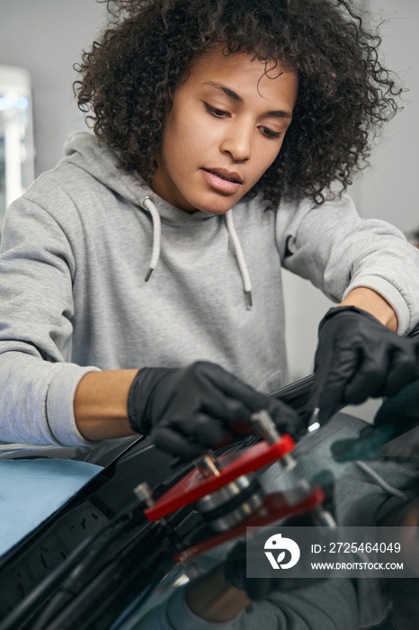 Concentrated auto mechanic installing windshield crack repair bridge