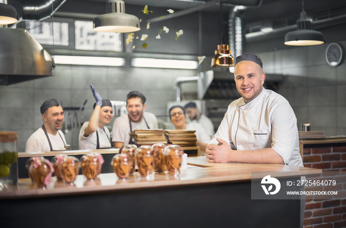 experienced cook with a cheerful face from a useless team posing in a modern kitchen with his team i