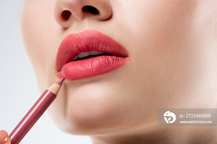 close up studio shot of woman applying lip pencil,  isolated on white