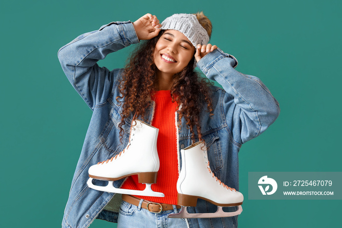 Beautiful young woman in winter clothes and with ice skates on color background