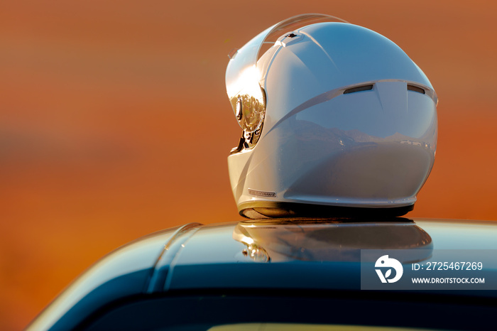 清晨的阳光下，一顶赛车头盔坐在汽车顶部
