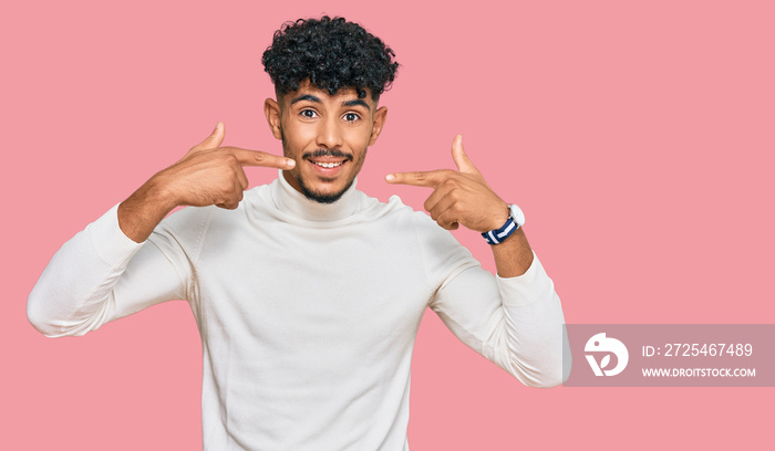 Young arab man wearing casual winter sweater smiling cheerful showing and pointing with fingers teet