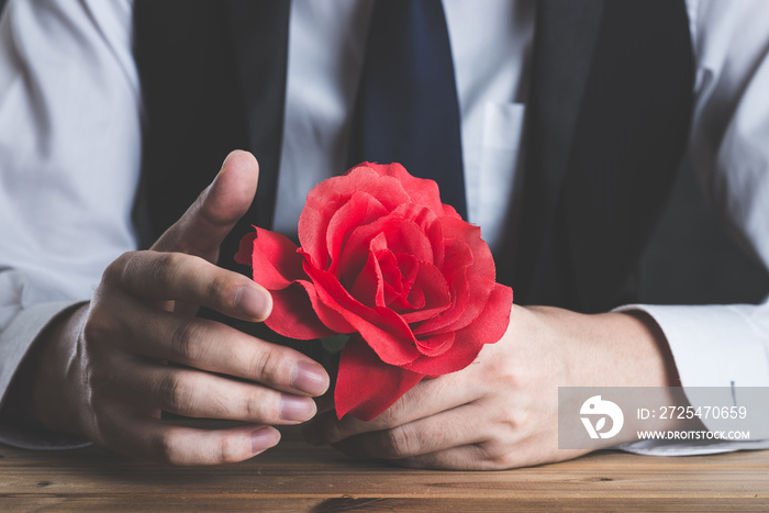 赤いバラの花を持っている男性