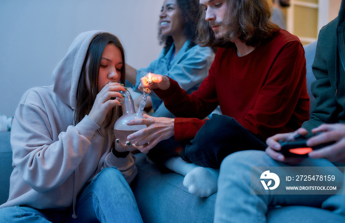 吸食大麻和玩电子游戏。年轻人用大麻为他的女性点燃烟枪