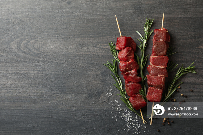 Skewers with raw meat and spices on dark background