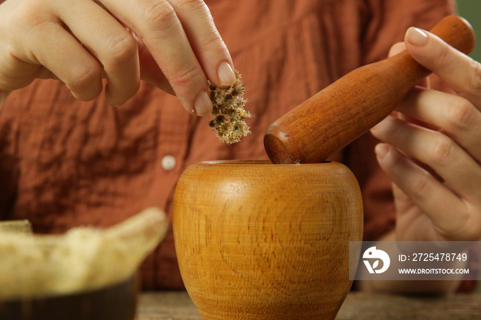 Woman preparing natural medicines with mortar and pestle. Process of making natural cosmetic or herb