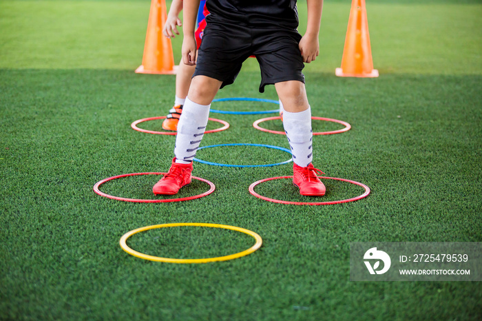 选择性关注儿童足球运动员在绿色人造草坪上的环形梯标记处慢跑和跳跃
