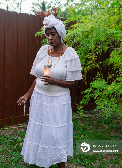 花园里的女人用蜡烛和念珠祈祷