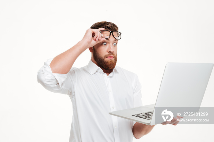 Shocked astonished man in eyeglasses looking at laptop screen