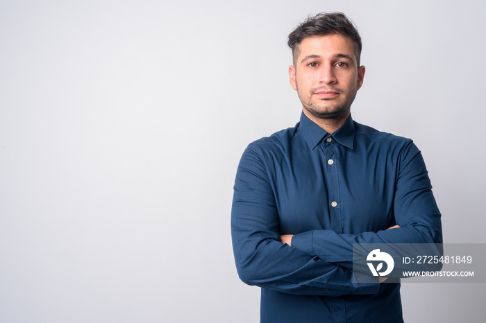 Portrait of young handsome Persian businessman with arms crossed