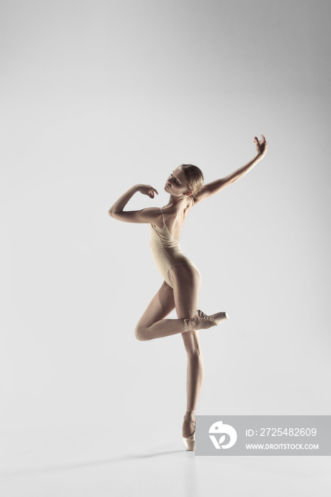 Young graceful female ballet dancer or classic ballerina dancing on white studio. Caucasian model on