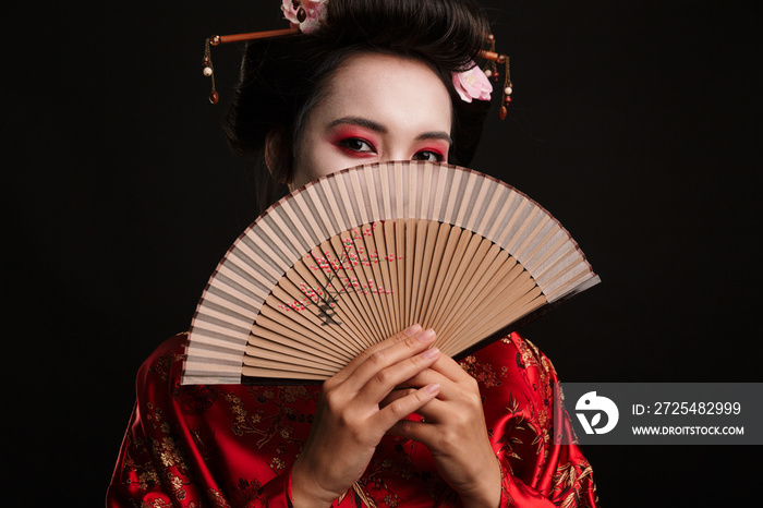 Image of young geisha woman in japanese kimono holding wooden hand fan