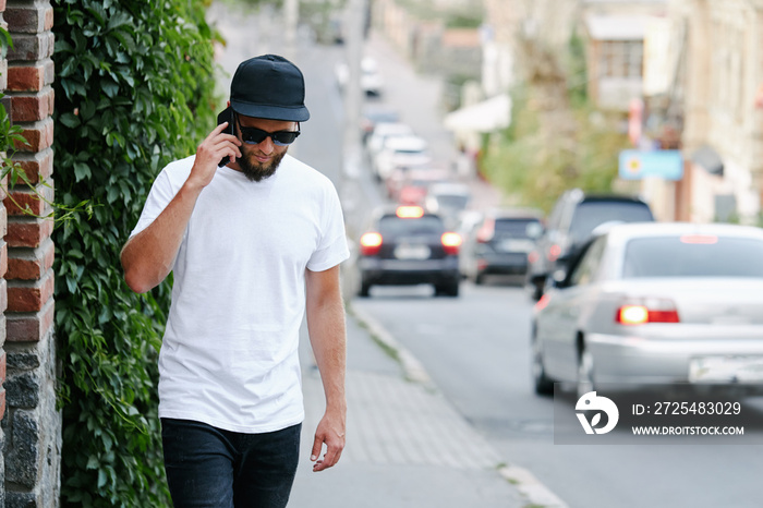 Hipster handsome male model with beard wearing white blank t-shirt and a baseball cap with space for