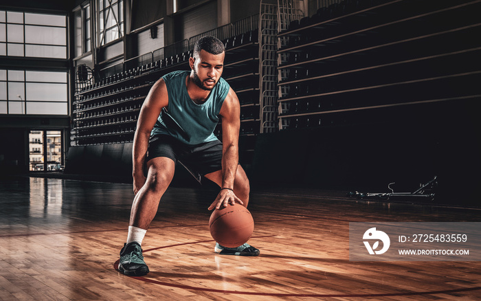 Full body portrait of Black professional basketball player in an action in basketball field.