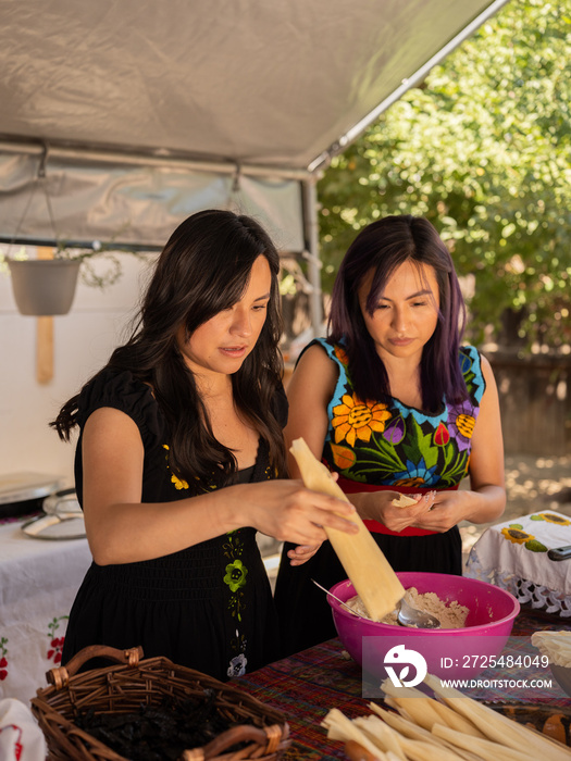 Indigenous sisters making tamales in an outdoor kitchen