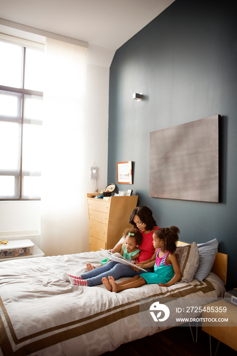 Mother reading to daughters (2-3, 4-5) in bedroom