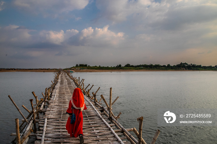 little girl with red dress, crosses old traditional bamboo wooden bridge across Mekong river (from K