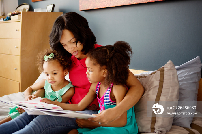 Mother reading to daughters (2-3, 4-5) in bedroom