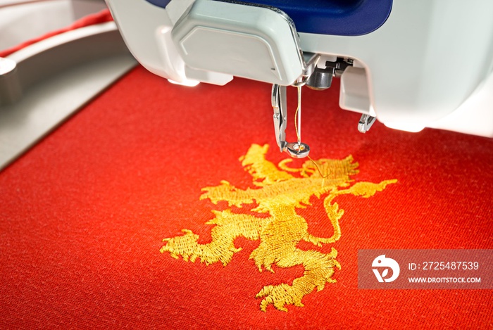 红色棉布衬衫上的刺绣机和金狮图案，特写图片