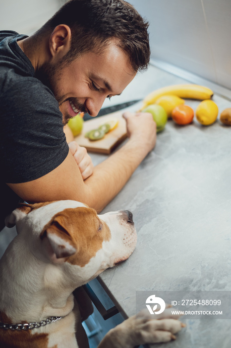 Smiling owner looking at his pit bull in the kitchen