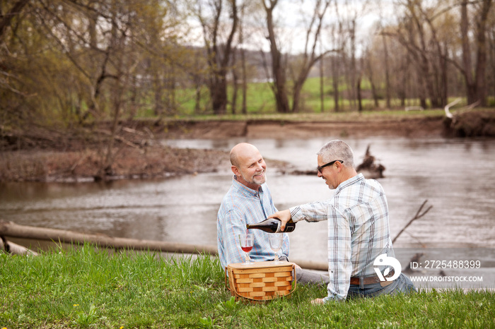 Gay couple having picnic at lake