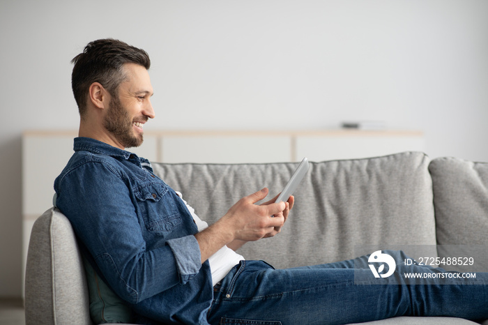 快乐男人在家沙发上休息，使用现代智能手机