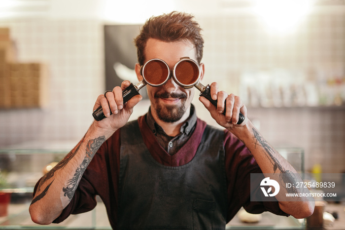 Hipster barista with portafilters in coffee shop