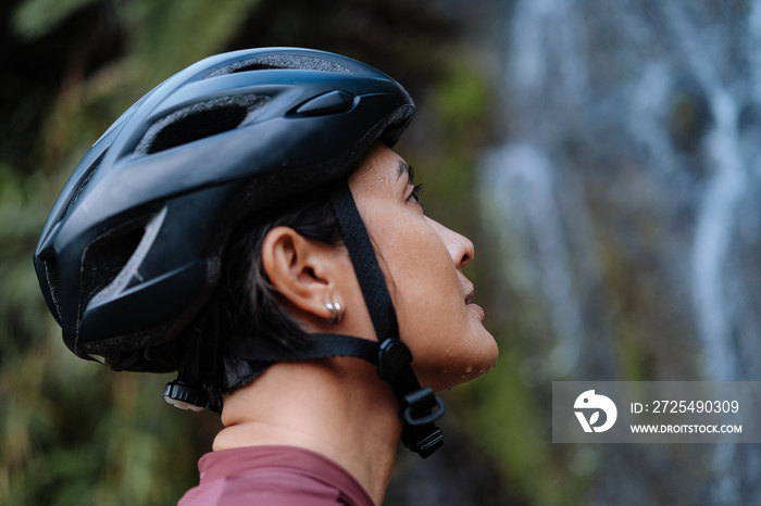 a young female cyclist practising breathing exercise by the waterfalls