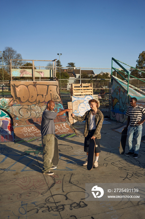 Three young skateboarders in skatepark with skateboards