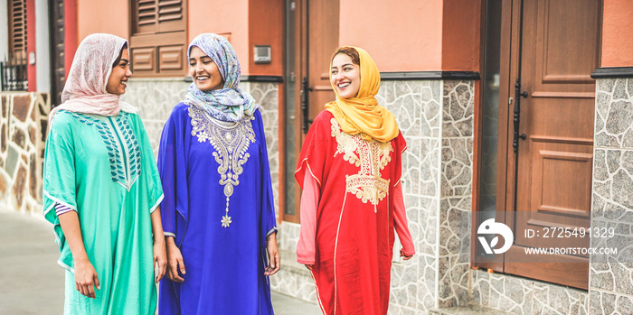 Happy arabic friends walking in city center with traditional islamic clothes - Young arabian women h