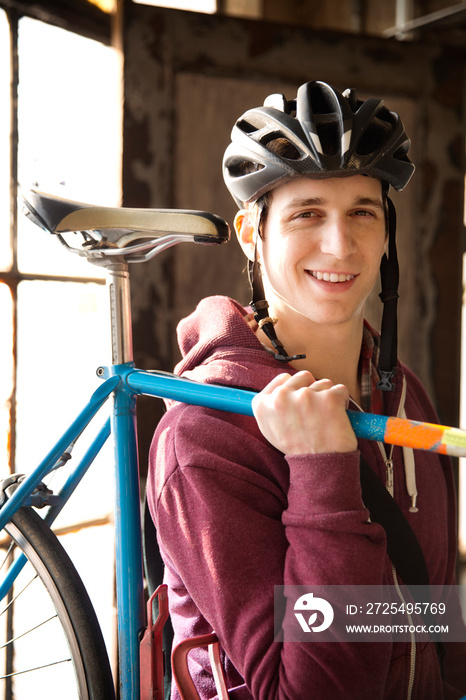 Man in corridor with bike on shoulder