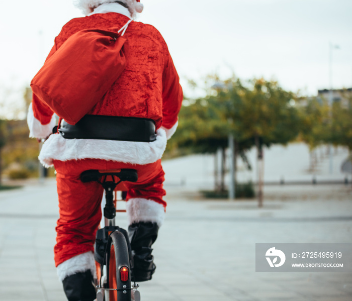 圣诞老人背着自行车和红色行李箱的背影