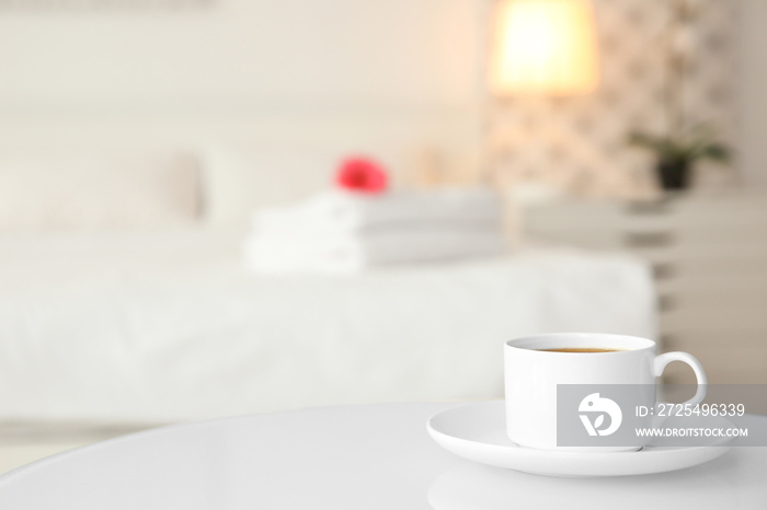 Cup of coffee on white table in light hotel room