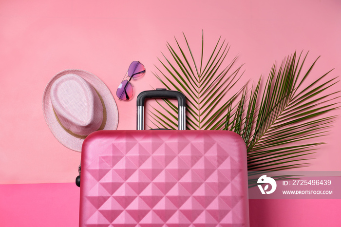 手提箱、热带树叶、太阳镜和彩色背景帽子。旅行概念