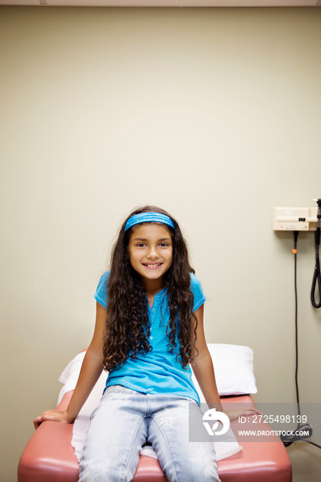 Smiling girl (8-9) sitting on examination table