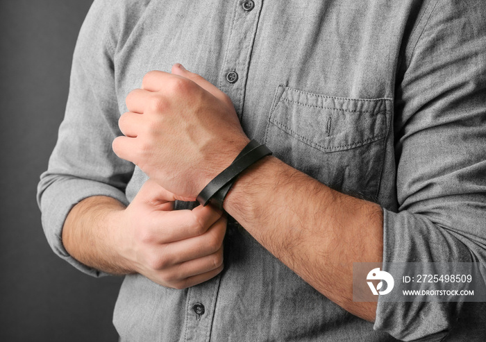 Closeup of man with stylish leather bracelet on dark background