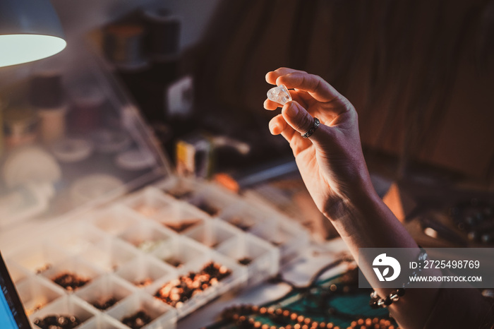 Talented jewellery beads maker is holding crystal clear semi precious stone in hand.