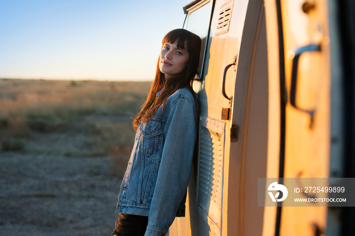 Portrait of young woman leaning on travel trailer