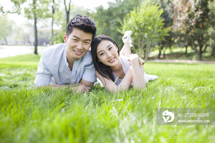快乐的年轻情侣趴在草地上