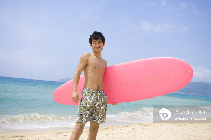 拿着冲浪板的男孩站在沙滩上