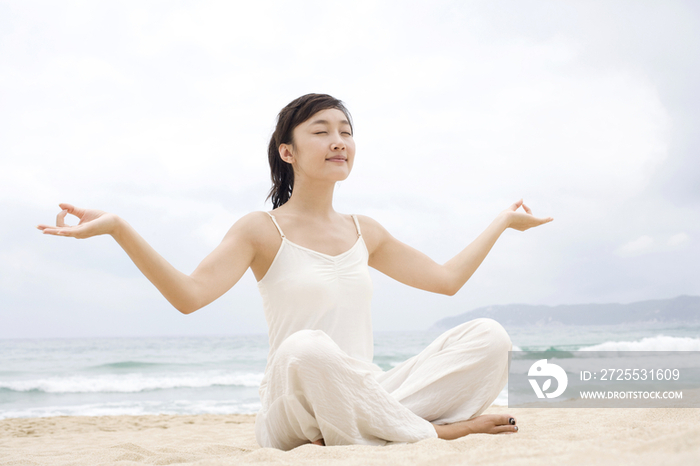 女子海边瑜珈盘腿展开双手