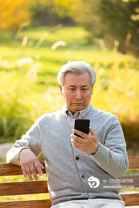 老年男子在公园使用手机