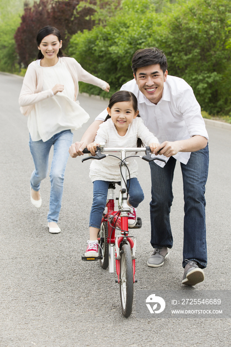 年轻父母教女儿骑自行车