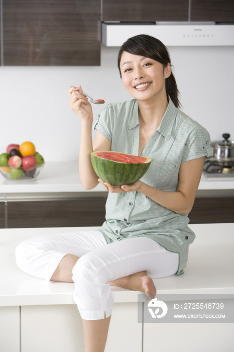 青年女子在厨房吃西瓜