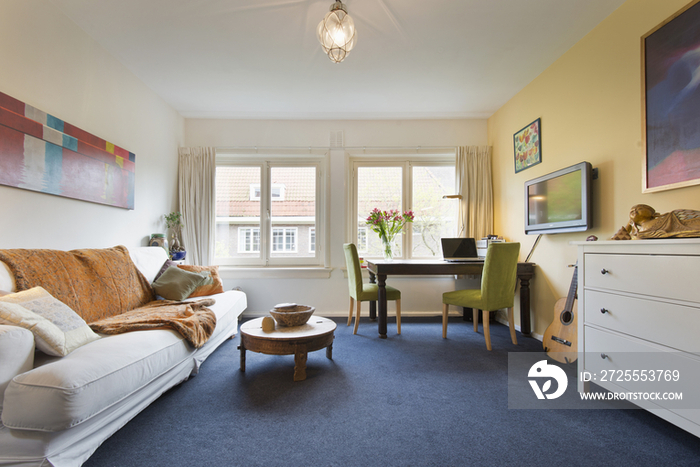 Wall to wall carpet in tidy living room with study desk by the window at home